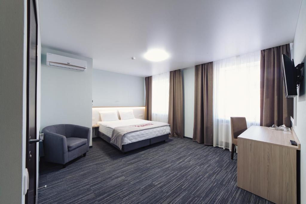 um quarto de hotel com uma cama e uma cadeira em Deryabin Hotel em Izhevsk