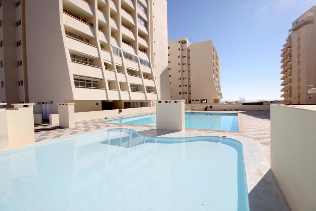 a swimming pool on the roof of a building with tall buildings at T1 Varandas da Rocha by amcf in Portimão