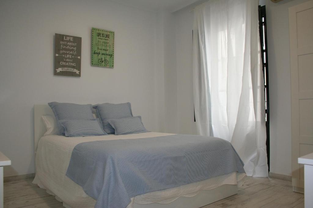 Dormitorio blanco con cama con almohadas azules en CLB Sierpes Apartment en Sevilla