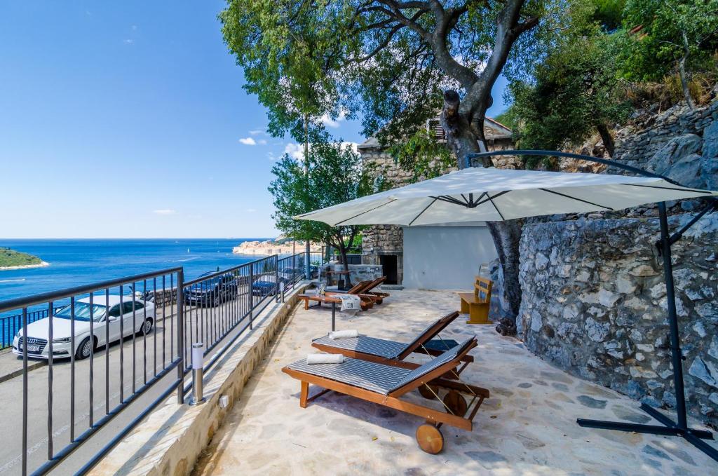 eine Terrasse mit Stühlen, einem Sonnenschirm und dem Meer in der Unterkunft Apartments Shining Star in Dubrovnik