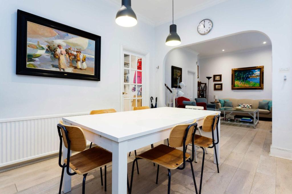 een eetkamer en een woonkamer met een witte tafel en stoelen bij Veeve - A Kensington Mews in Londen