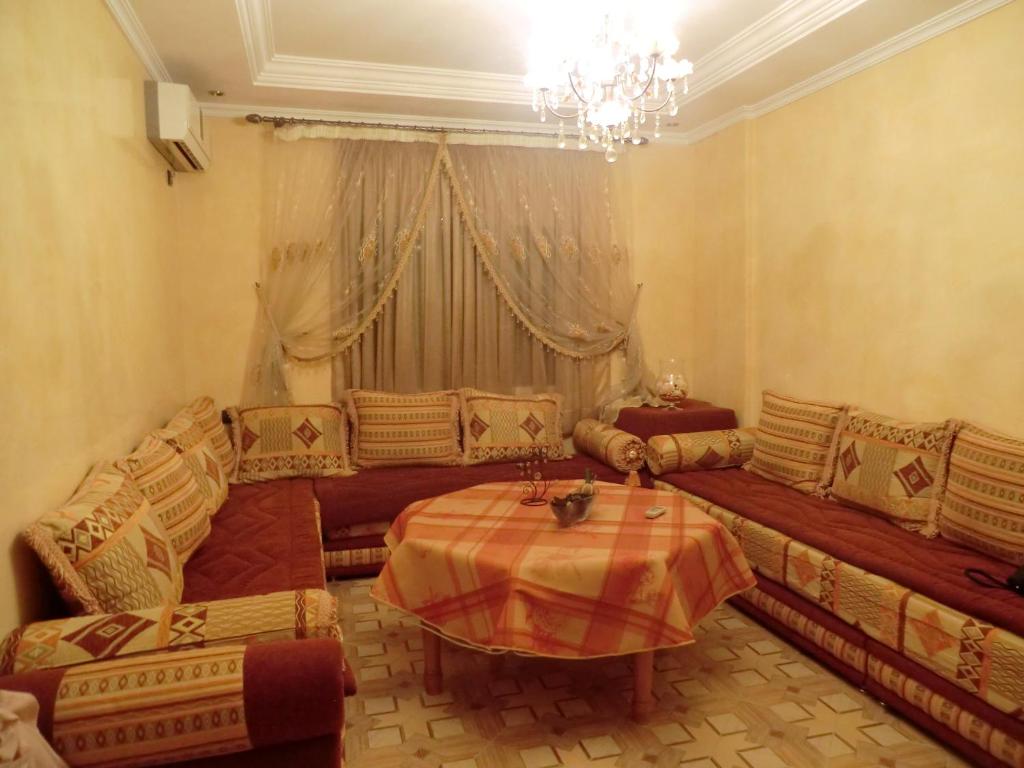 a living room with a table and couches and a chandelier at B205 LOT AL WIFAQ Bensergao AGADIR in Agadir