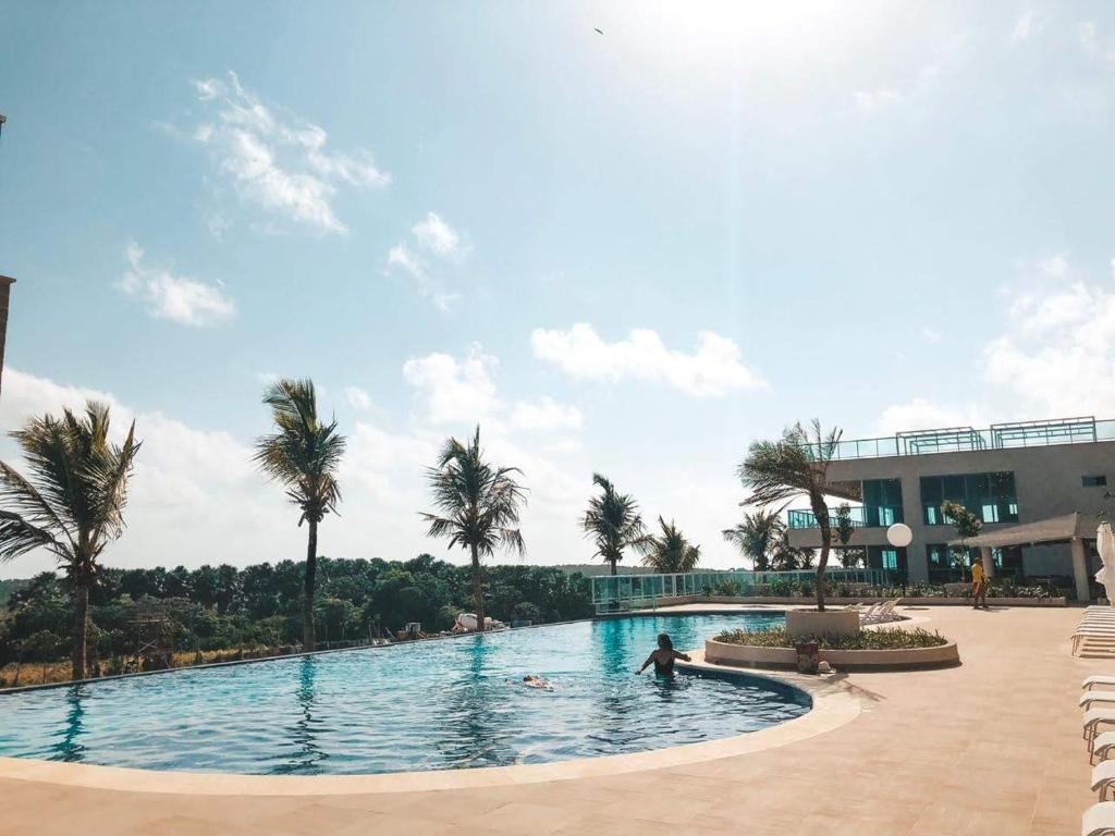 a swimming pool with palm trees and a building at SALINAS PARK RESORT in Salinópolis