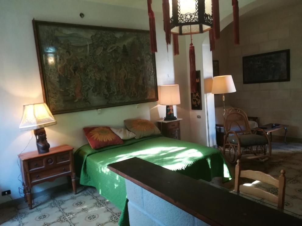 a bedroom with a green bed and a painting on the wall at Casa Zagara in Favignana