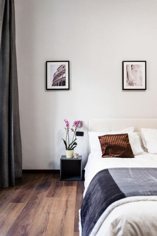 two beds in a bedroom with white walls and wooden floors at Alea Home Roma in Rome