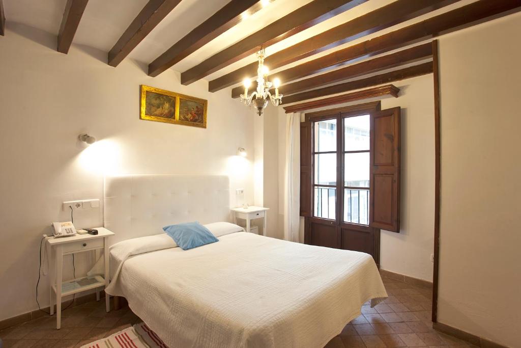 1 dormitorio con cama blanca y lámpara de araña en Turismo de Interior Ca Sa Padrina en Palma de Mallorca