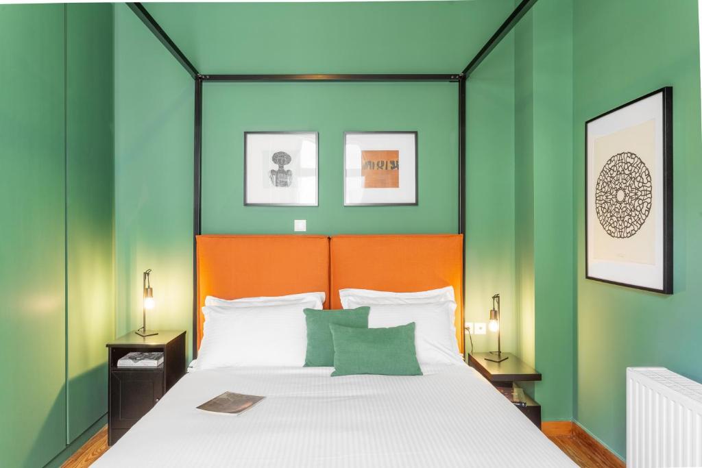 1 dormitorio con 1 cama con paredes de color verde y naranja en Hidesign Athens Apollon Luxury Apt in Plaka Acropolis, en Atenas