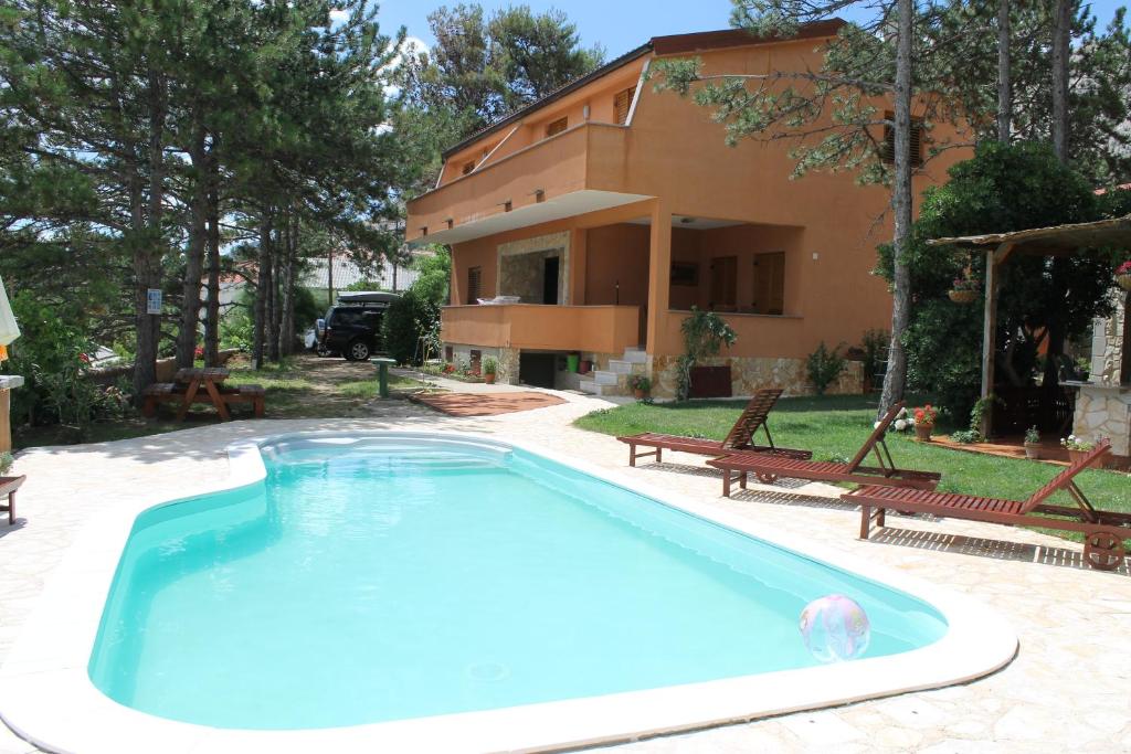 a swimming pool in front of a house at Apartments Lili in Baška