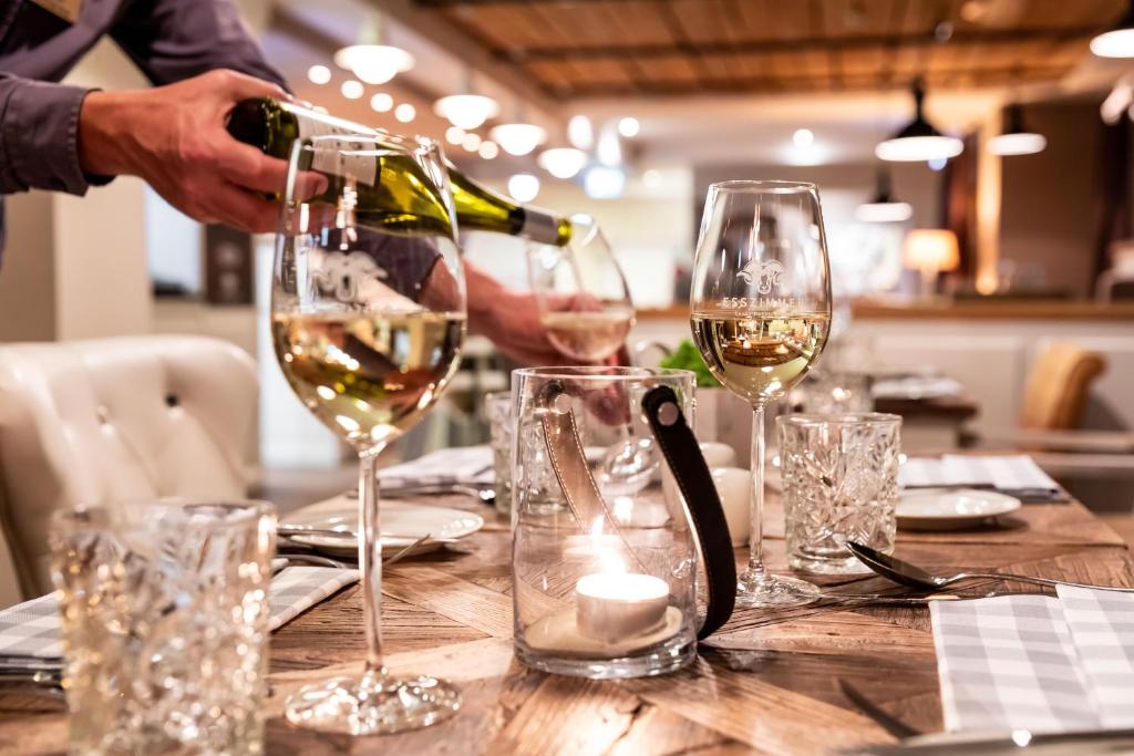 a person pouring white wine into glasses on a table at Hotel Zweite Heimat in Sankt Peter-Ording