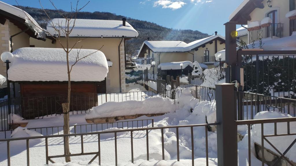 a snow covered yard with a fence and buildings at Garden House Alfedena in Alfedena
