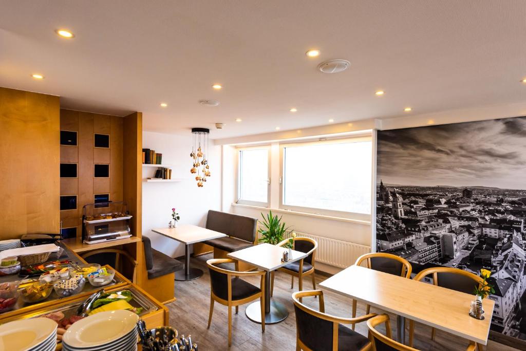 a restaurant with tables and chairs and a large window at City Hotel Heilbronn in Heilbronn