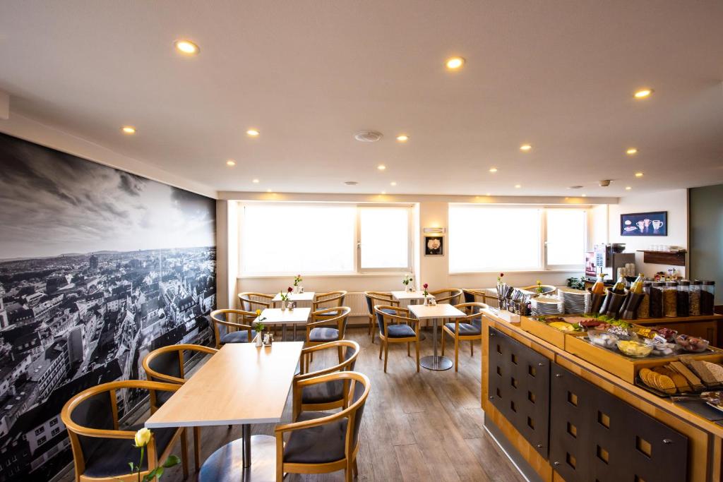 a restaurant with tables and chairs and a large picture on the wall at City Hotel Heilbronn in Heilbronn