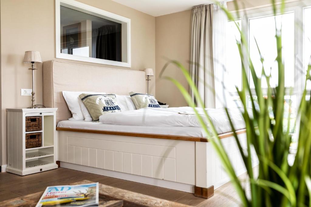 a bedroom with a bed with a mirror and a plant at Hotel Zweite Heimat in Sankt Peter-Ording
