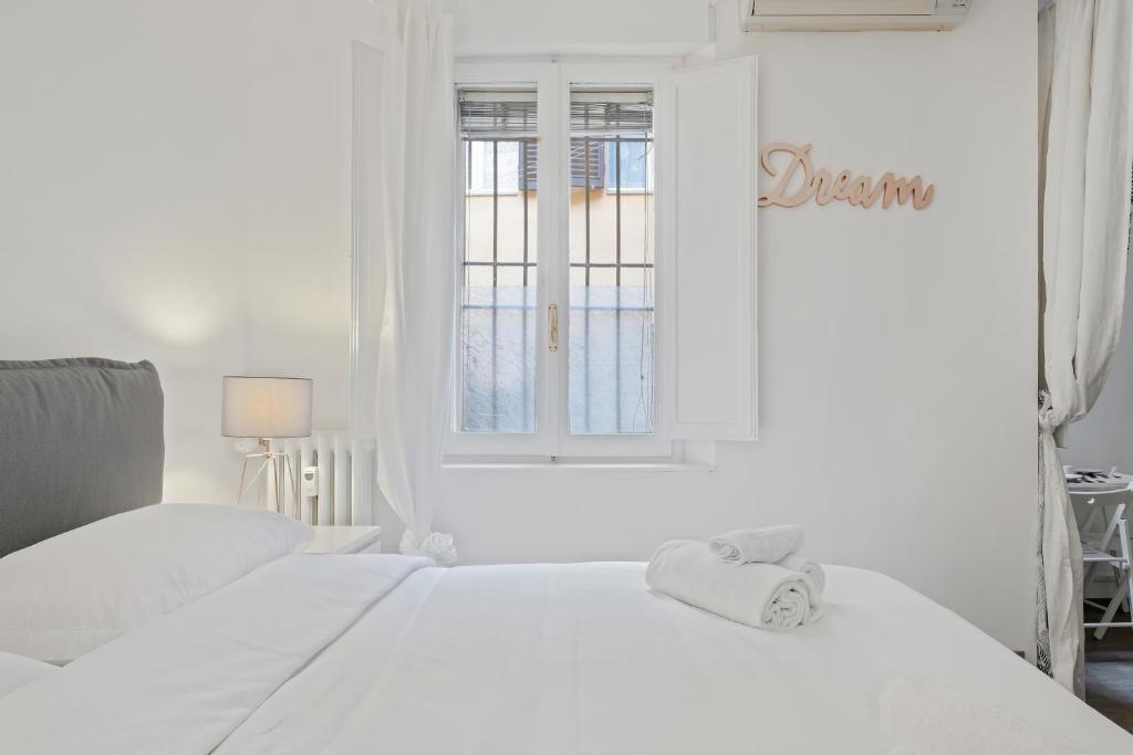 a white bedroom with a white bed and a window at Sognando Bologna Flat in Bologna