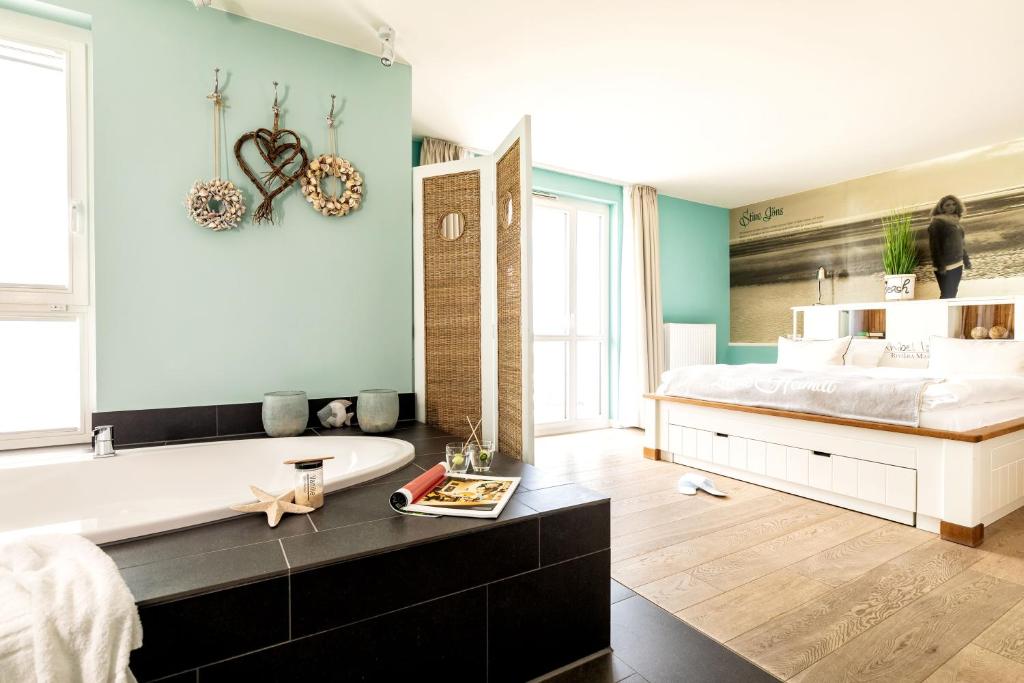 a bedroom with a large bed and a bath tub at Hotel Zweite Heimat in Sankt Peter-Ording