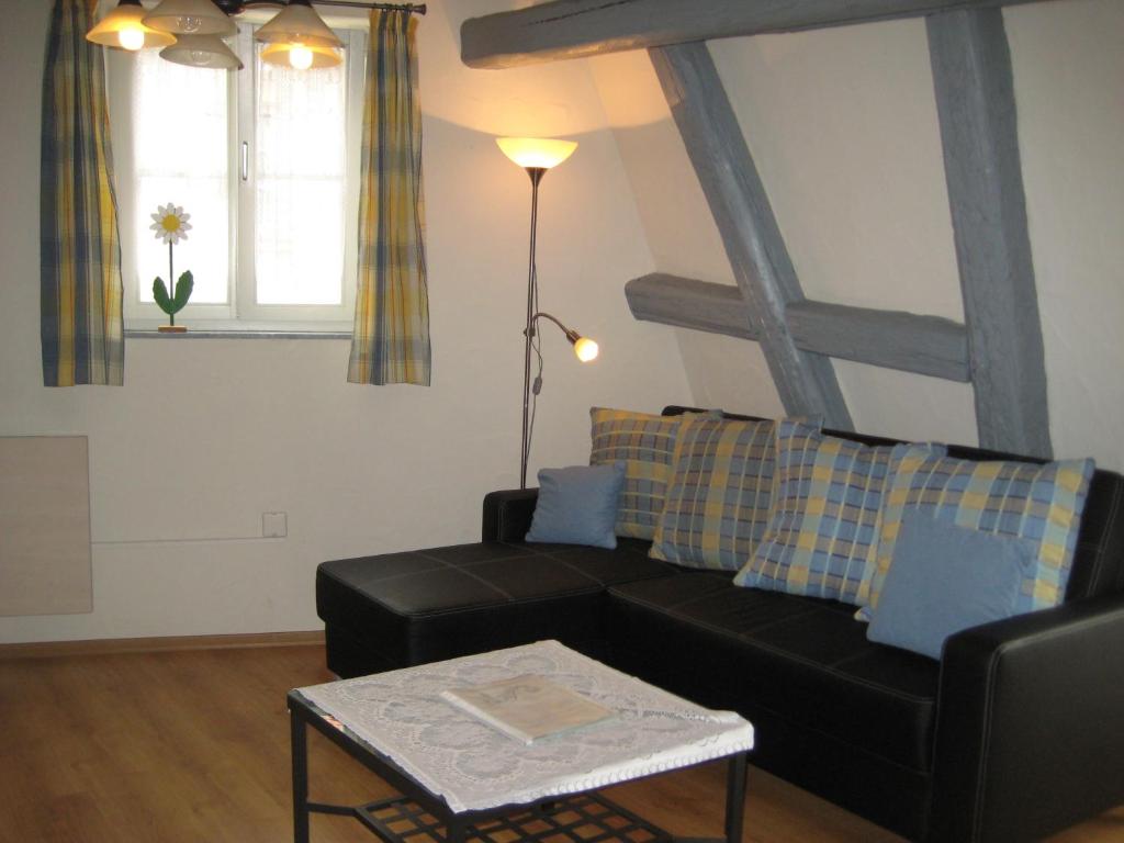 ein Wohnzimmer mit einem schwarzen Sofa und einem Tisch in der Unterkunft Romantisches Torhaus in Sommerhausen