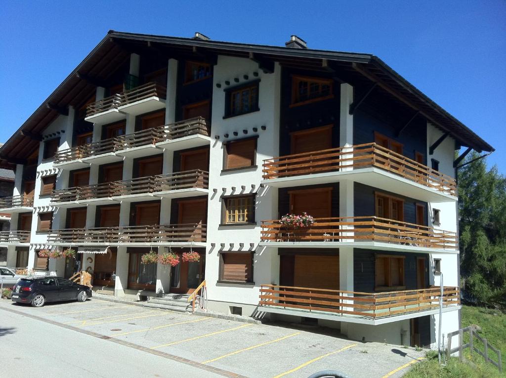 a building with balconies and a car parked in front of it at Immeuble Les Ecureuils in Les Collons