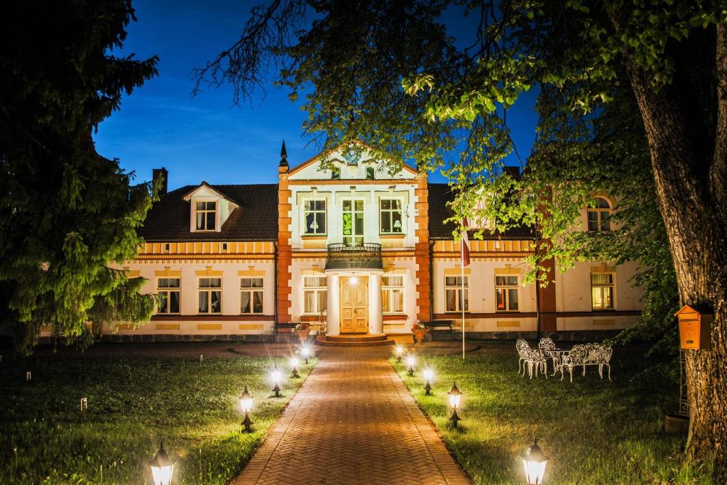 a large house with lights on a driveway at Marcienas Muiza & SPA in Mārciena