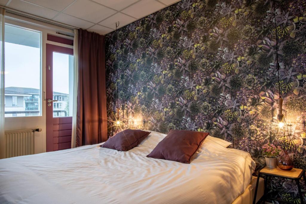 een slaapkamer met een bed met bloemenbehang bij Hotel Villa Flora in Hillegom