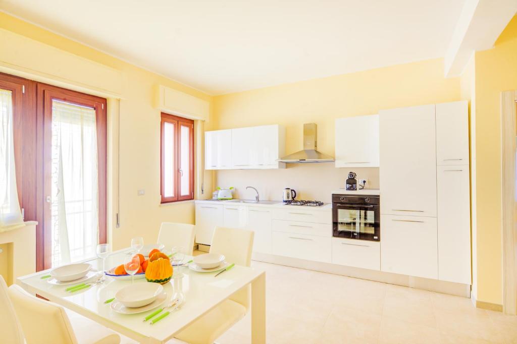 eine Küche mit einem weißen Tisch und weißen Schränken in der Unterkunft Domus Iose Seaview Apartment in Syrakus