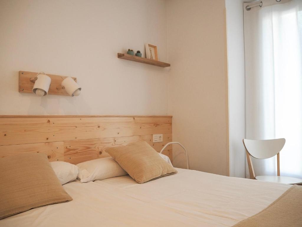 a bedroom with a white bed with a wooden headboard at Pensión Urkia in San Sebastián