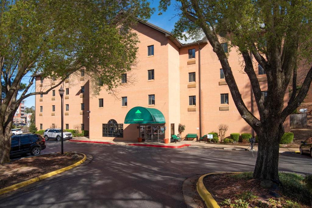 a large brick building with a green awning at Guest Inn & Suites - Midtown Medical Center in Little Rock