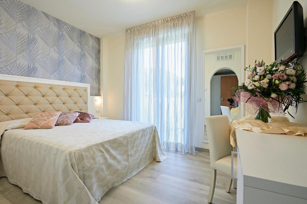 a bedroom with a bed and a table and a television at Hotel Athena in Cervia