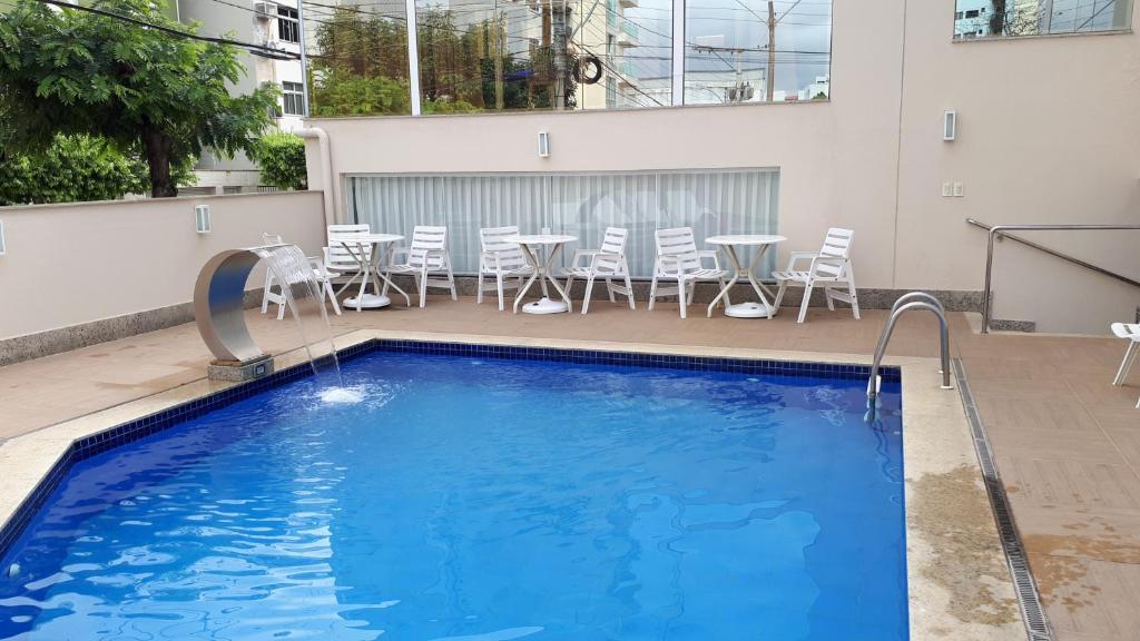 a swimming pool with chairs and a table on a building at Hotel Plenotel in Colatina