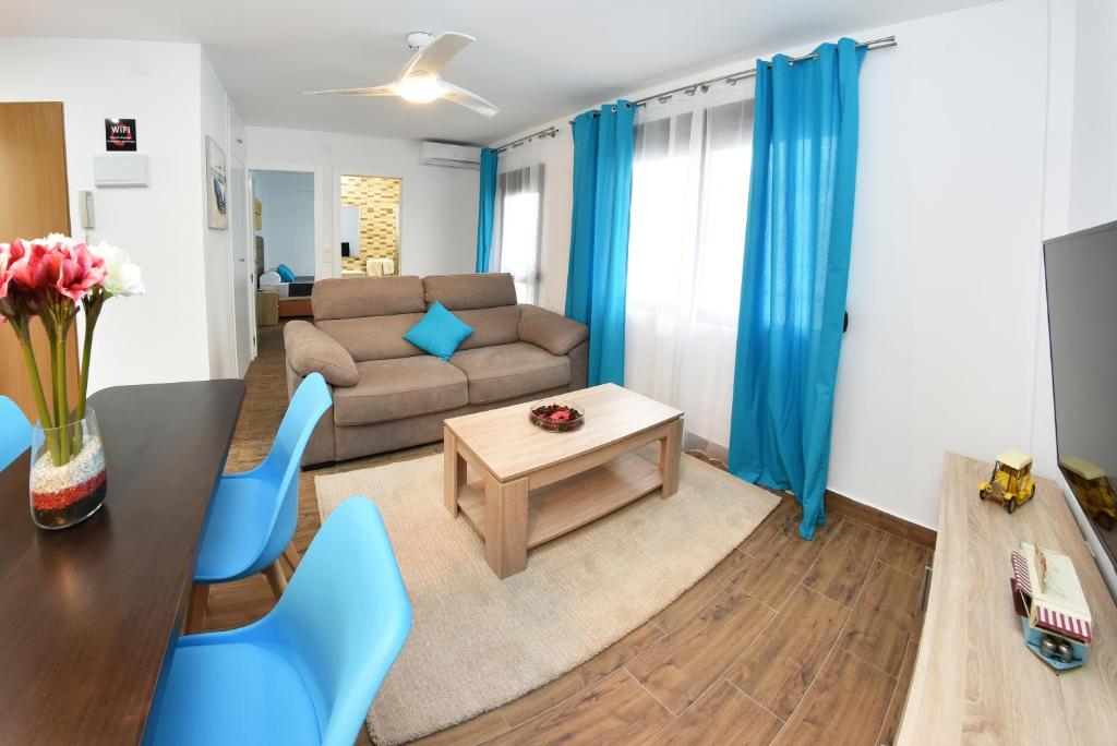 een woonkamer met een bank, een tafel en blauwe stoelen bij Zenbeach 1A playa carihuela in Torremolinos
