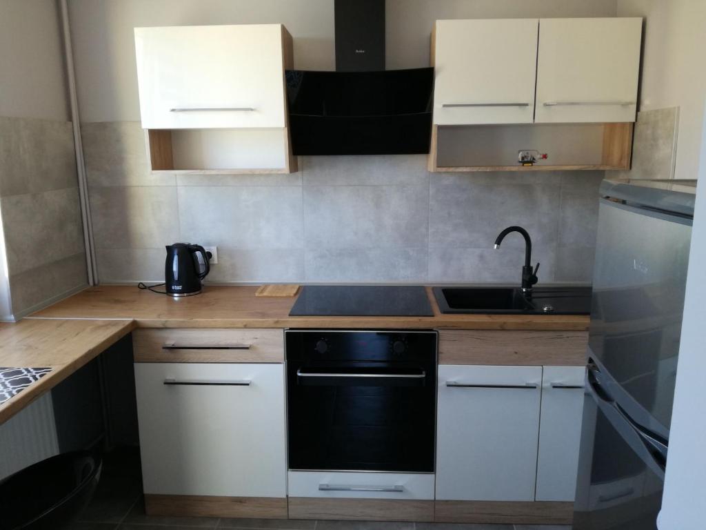 a kitchen with white cabinets and a black dishwasher at Apartament Nad Dziwną in Dziwnów