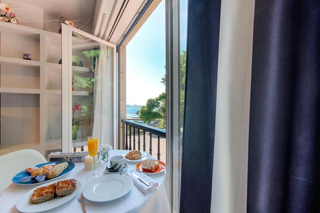 einen Tisch mit Teller mit Lebensmitteln auf einem Tisch mit einem Fenster in der Unterkunft apartamento santa cruz oleiros in Oleiros