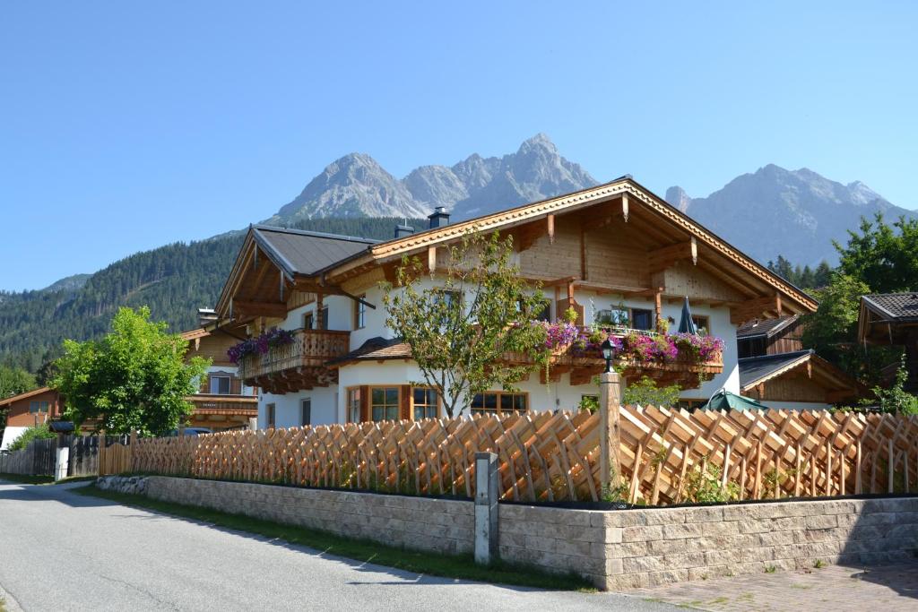 a house with a fence and mountains in the background at Appartement Herzog in Saalfelden am Steinernen Meer