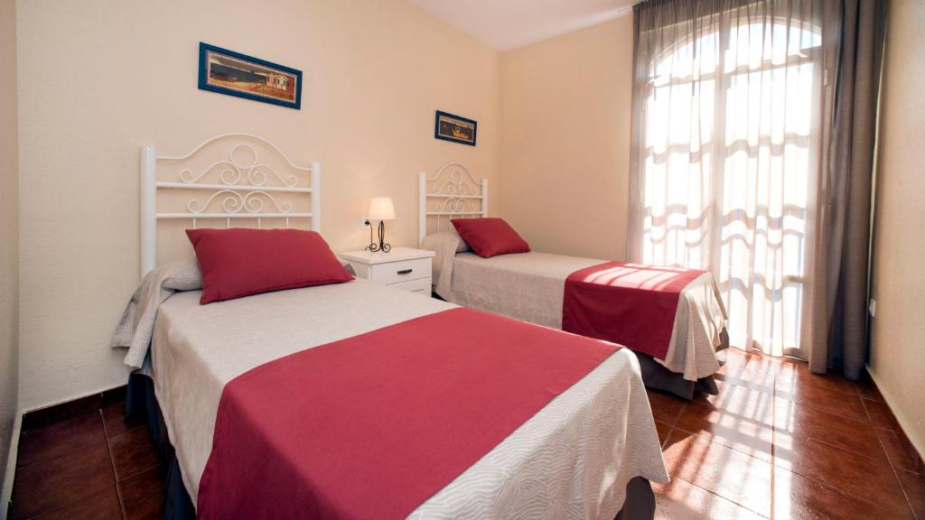 um quarto com 2 camas com lençóis vermelhos e brancos em Leo Islamar na Islantilla
