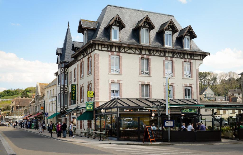 a large building with a roof on a city street at Hotel De Normandie in Arromanches-les-Bains