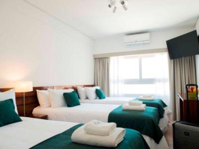 um quarto com 3 camas com lençóis verdes e brancos em Hotel 6 de Octubre em Buenos Aires