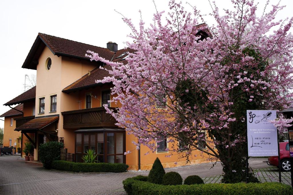 un arbre aux fleurs roses devant un bâtiment dans l'établissement Appartementhaus Sibylle, à Bad Füssing