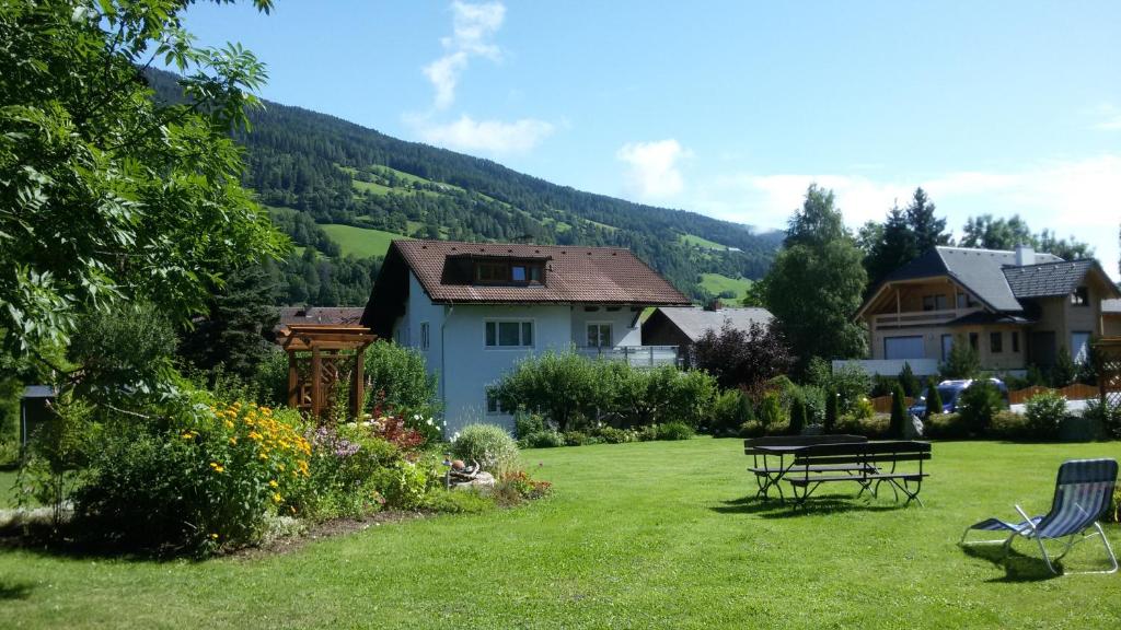 un patio con una casa y un banco en el césped en Pension Strauss, en Sankt Lorenzen ob Murau