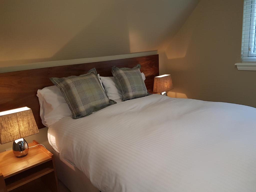 een slaapkamer met een wit bed met kussens en 2 lampen bij Allt Nan Ros Cottage in Fort William