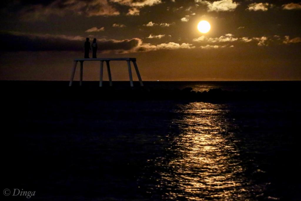 two people standing on a pier at sunset at Captains Lodge in Newbiggin-by-the-Sea