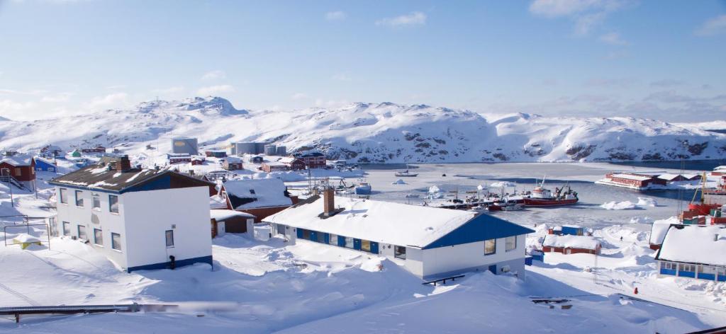een stad bedekt met sneeuw met bergen op de achtergrond bij Nattoralik in Aasiaat