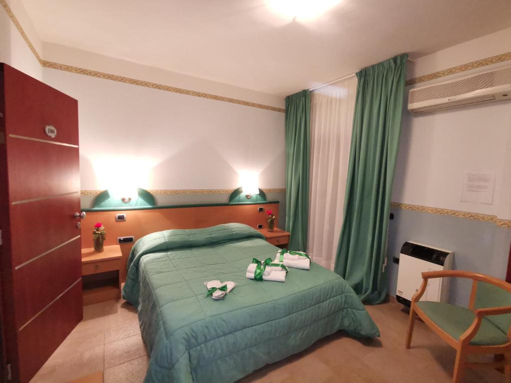 a hotel room with a green bed and a chair at Santa Lucia Hotel in Corigliano Calabro