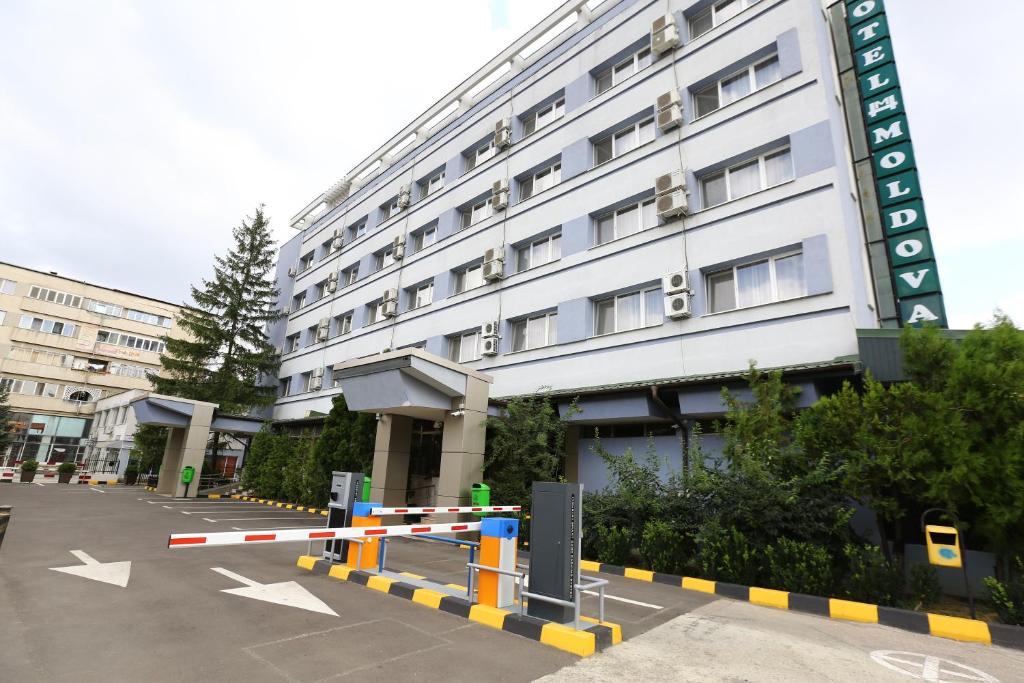 a white building with a parking lot in front of it at Hotel Moldova in Bîrlad