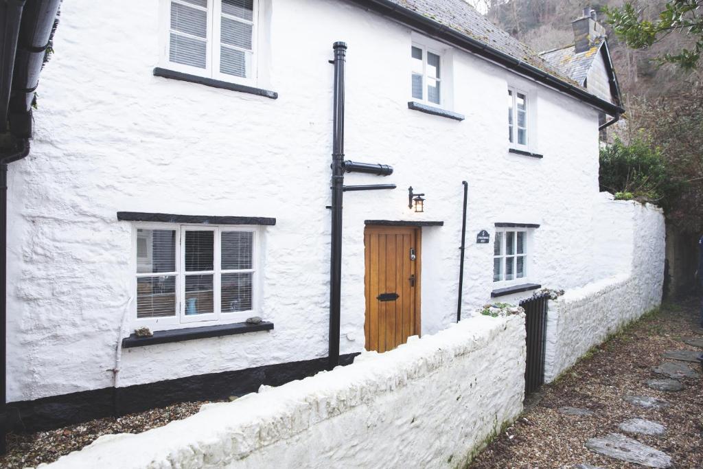 una casa bianca con una porta in legno e una recinzione di I'm Your Host - Fisherman's Rest a Lynmouth