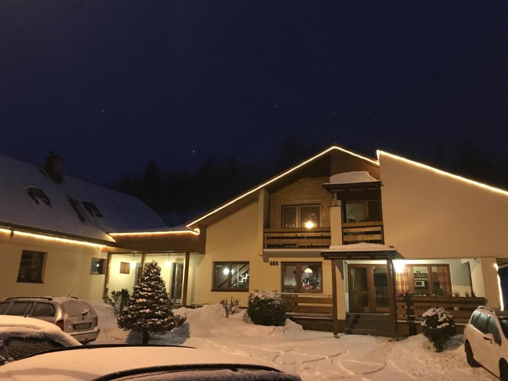 a house with a christmas tree in the snow at night at Penzion Biely Potok in Terchová