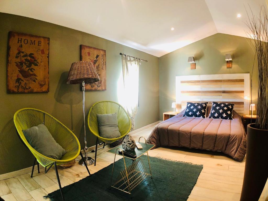 1 dormitorio con 1 cama y 2 sillas verdes en Mas Guiraud, le Coquet, en Beaucaire