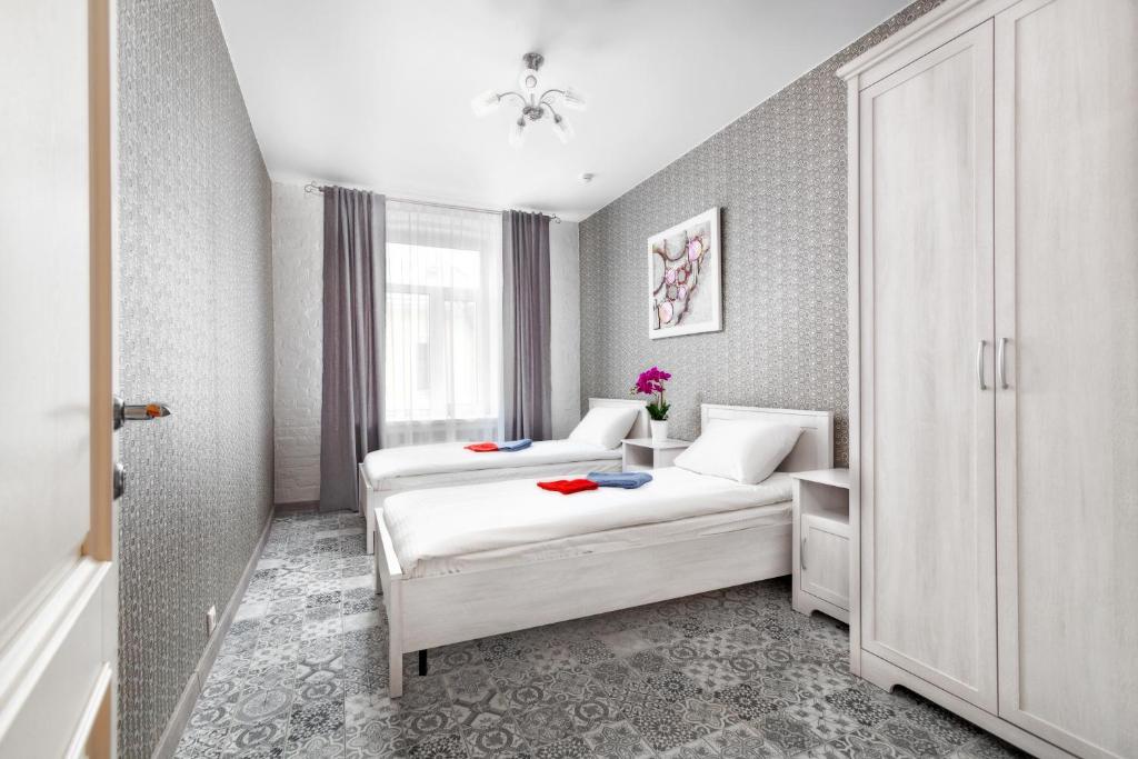 a white bedroom with two beds and a window at WOW Hostel in Moscow