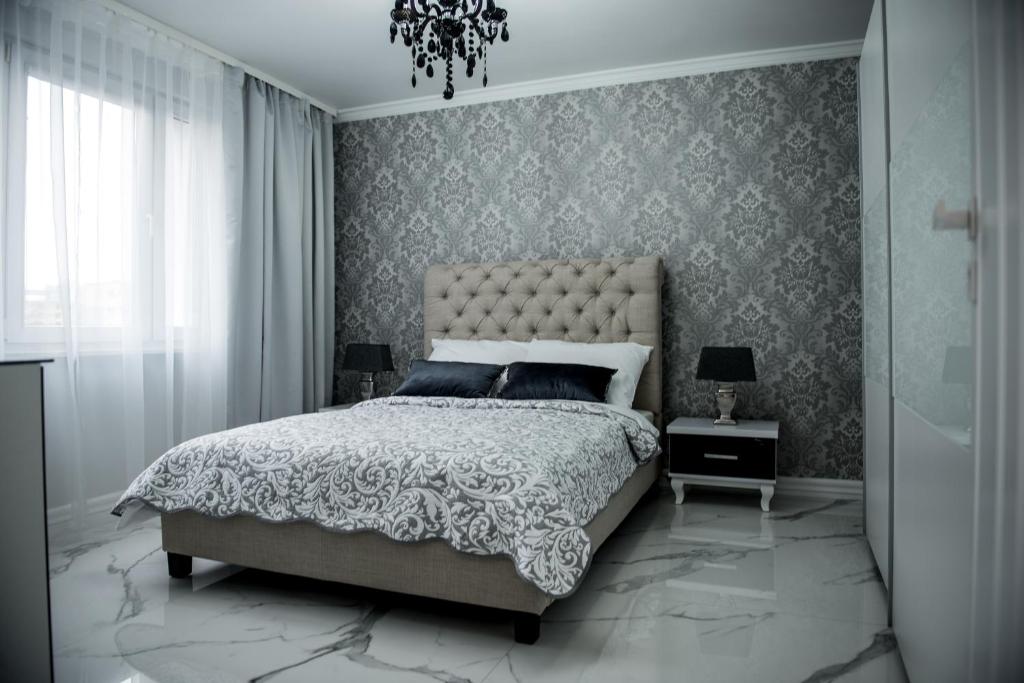 Glamour Apartments في بيوا: غرفة نوم بسرير كبير وثريا