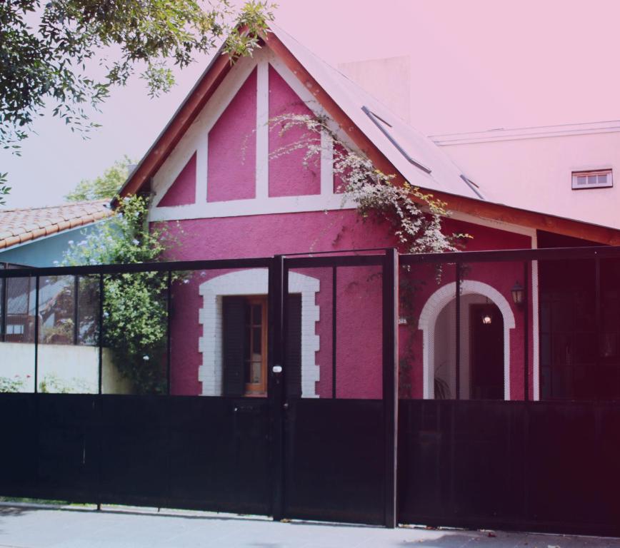 uma casa vermelha com uma cerca preta à frente. em Florida y Roja em Vicente López