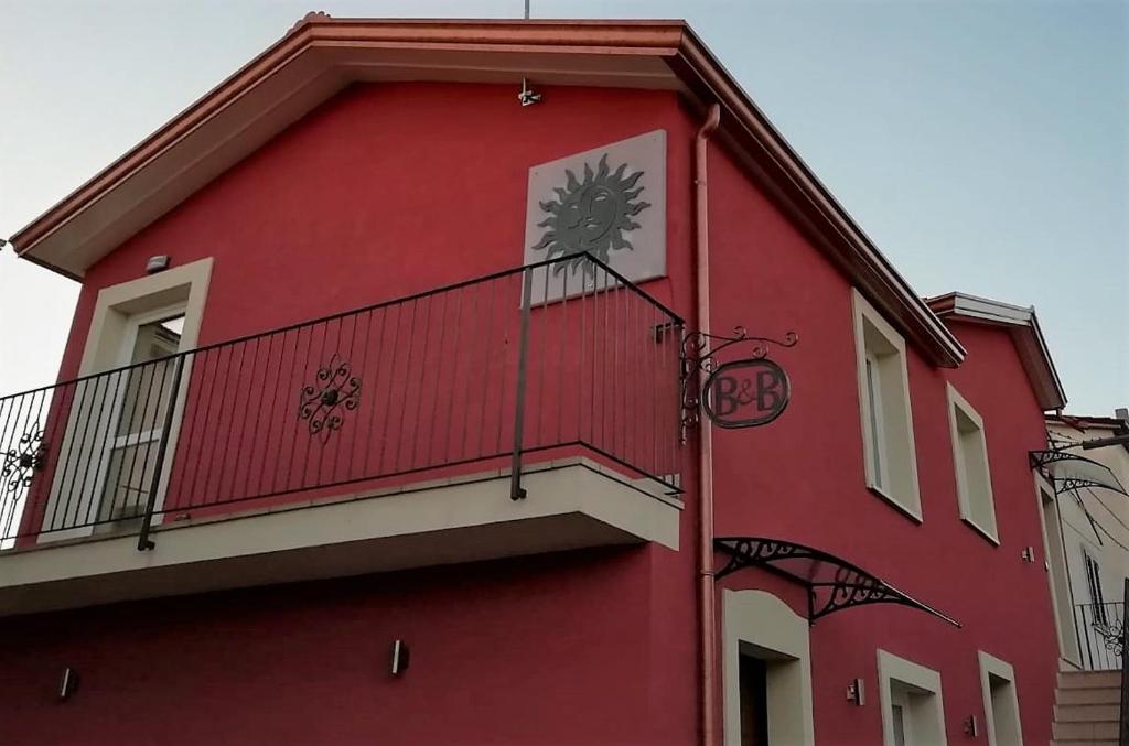 um edifício vermelho com uma varanda com um relógio em Borgo Sole Luna em Fornelli