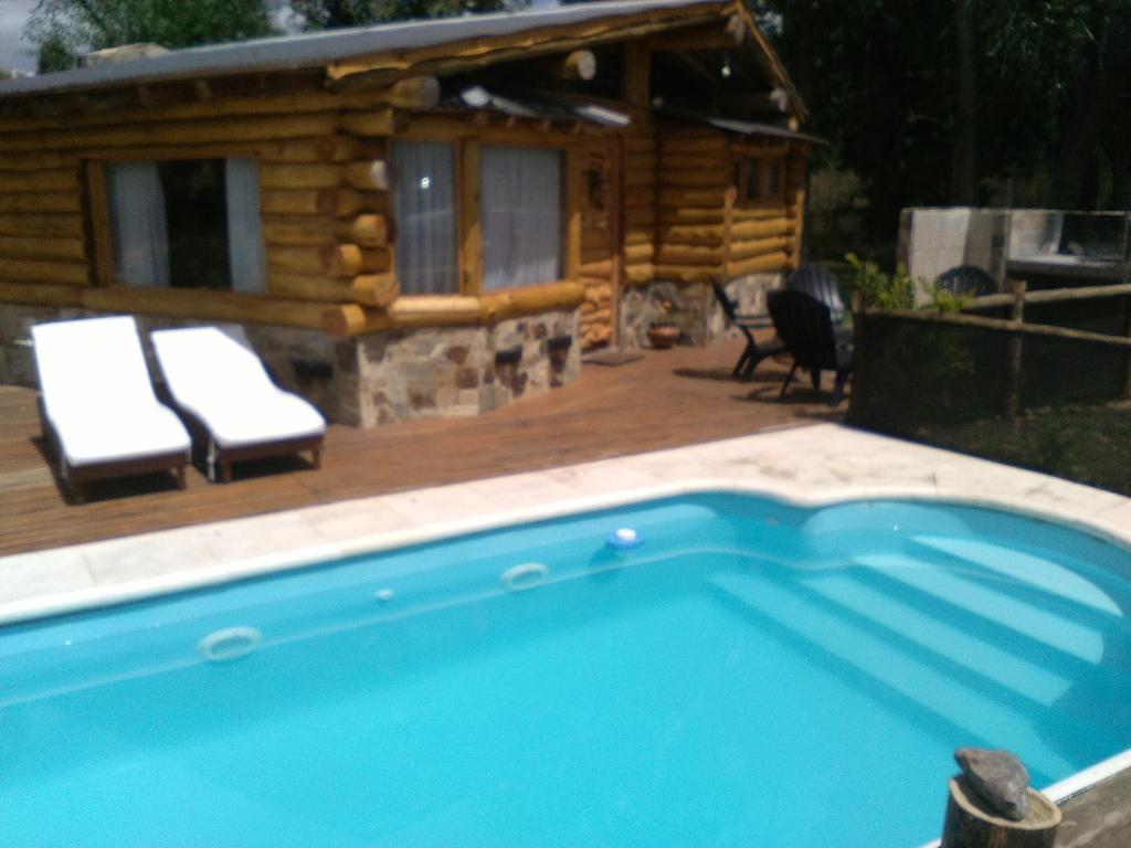 une cabane en rondins avec une piscine et une maison dans l'établissement Cabañas Cuncumen, à Tandil